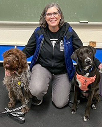 Lori O'Brien kneeling with two dogs